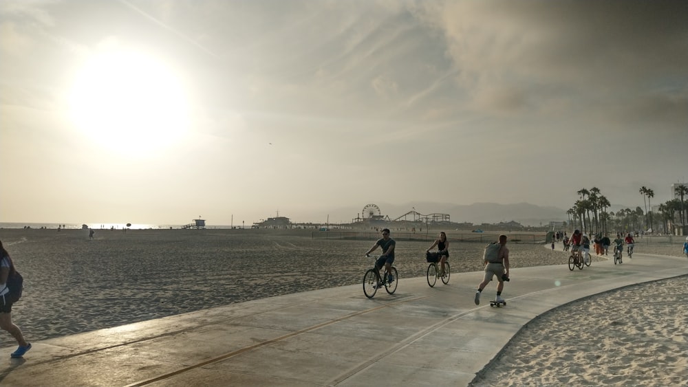 a group of people riding bikes down a sidewalk next to the ocean