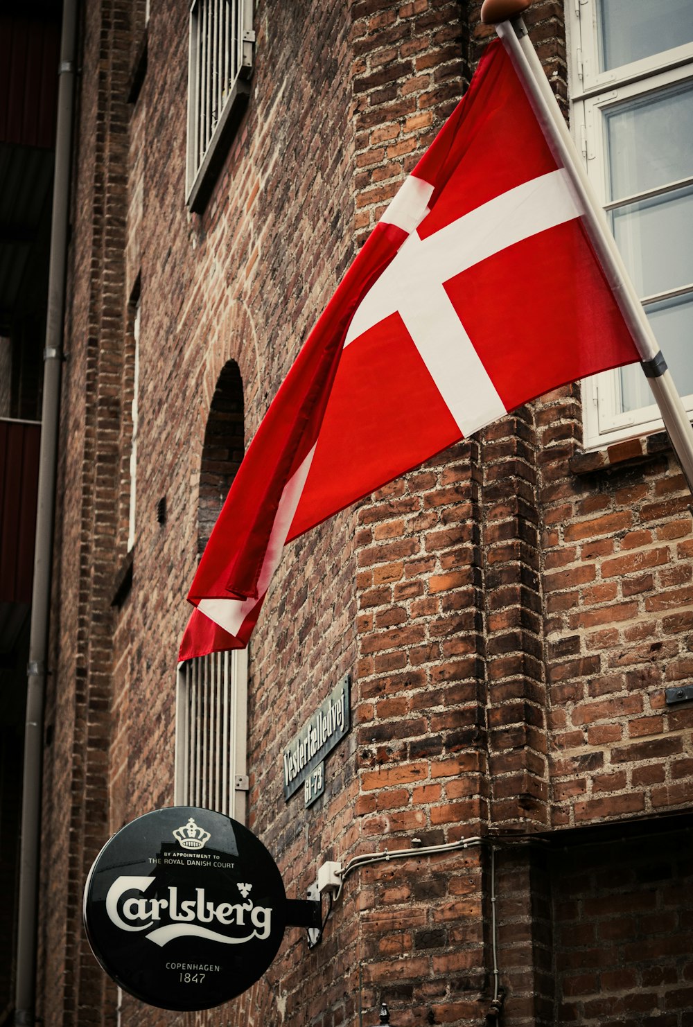 a red and white flag hanging from the side of a brick building