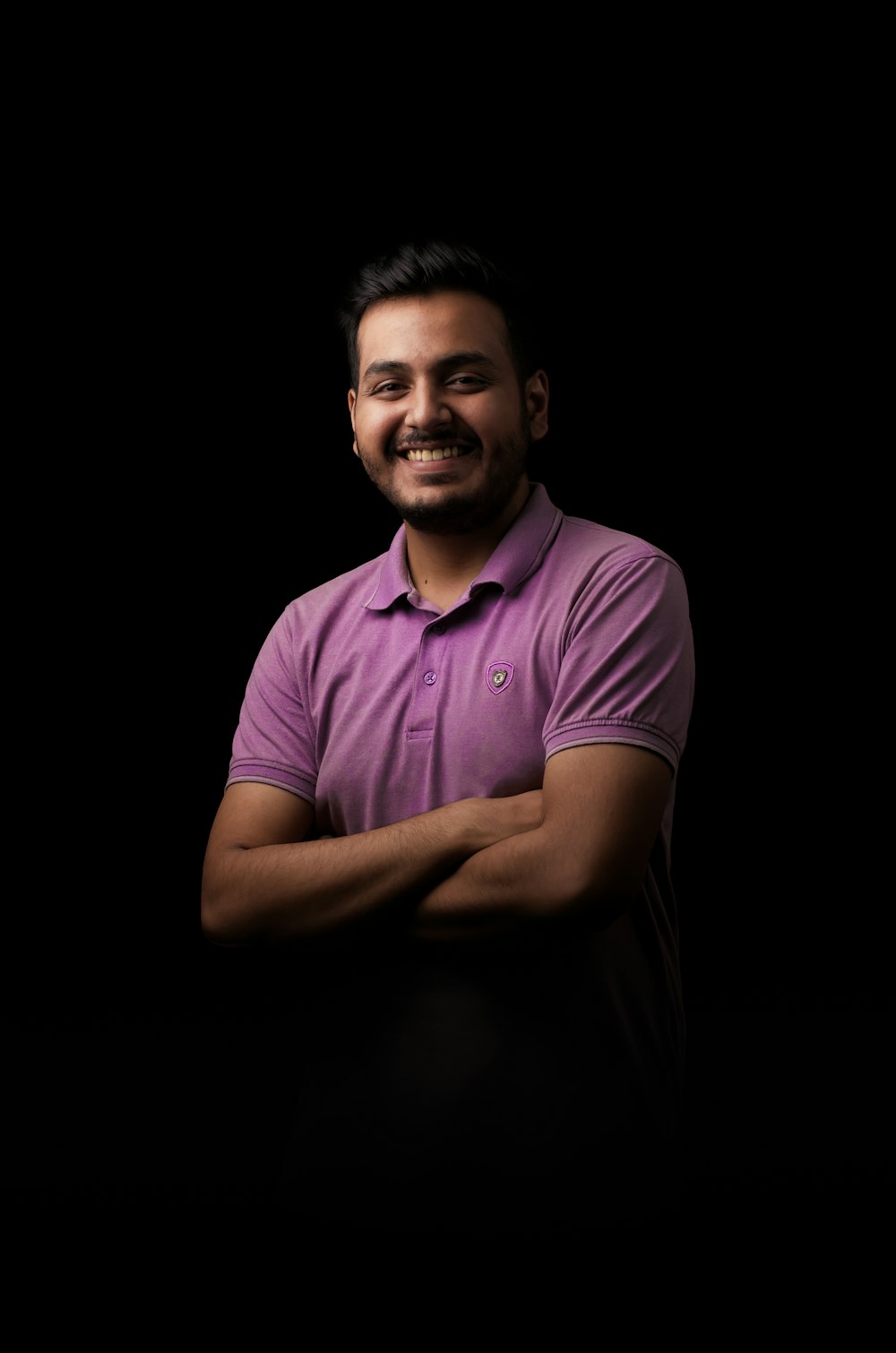 a man standing with his arms crossed in front of a black background