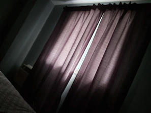 A technician carefully installing blackout curtains in a bright bedroom.