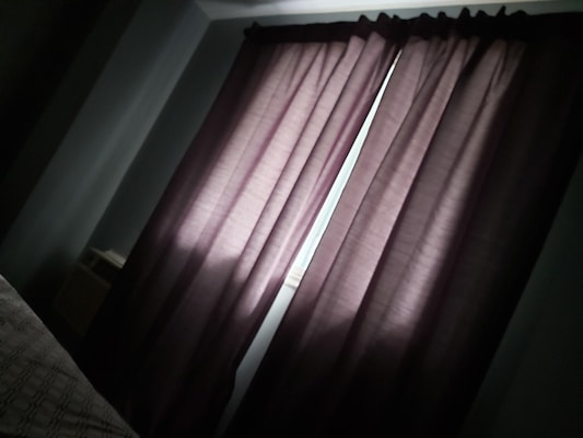 Bedroom with blackout curtains fully drawn, illustrating complete darkness and privacy.