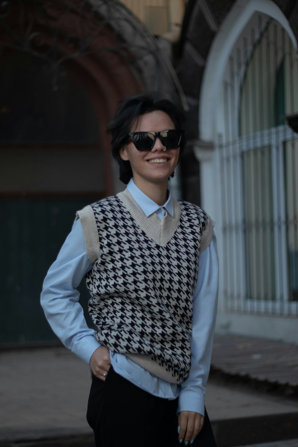 a woman wearing a sweater vest and sunglasses
