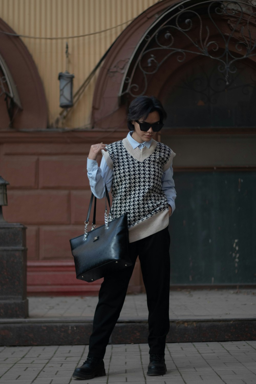 a woman in black pants and a sweater carrying a black bag