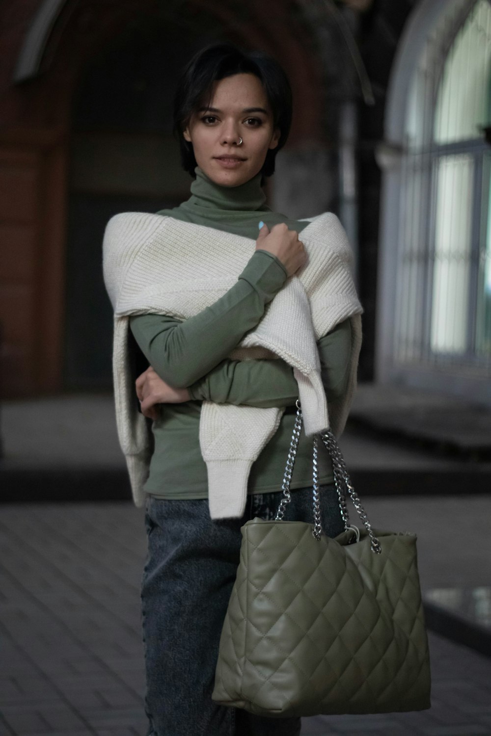 a woman carrying a green purse and a white blanket