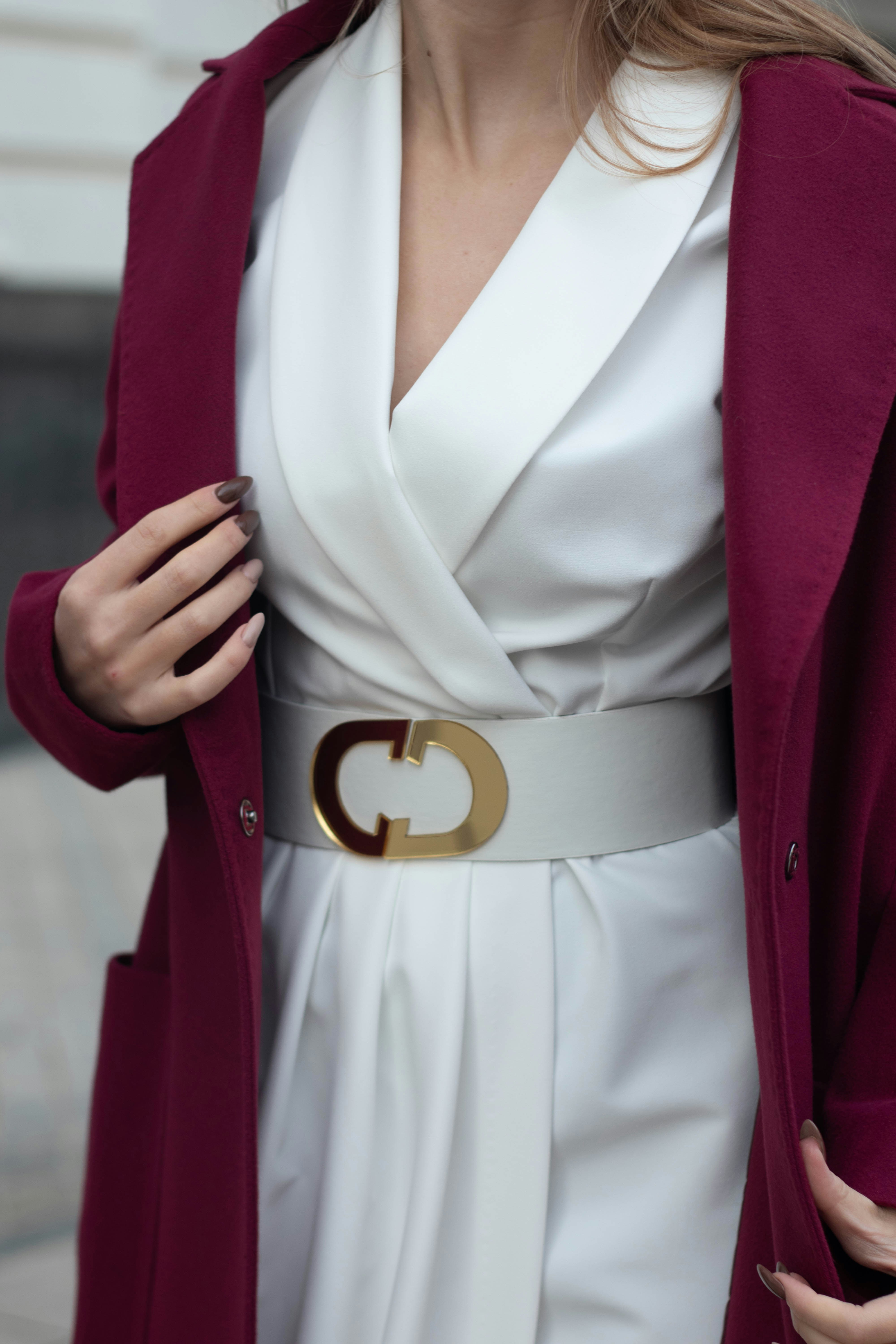 Una mujer con un vestido blanco y un abrigo burdeos