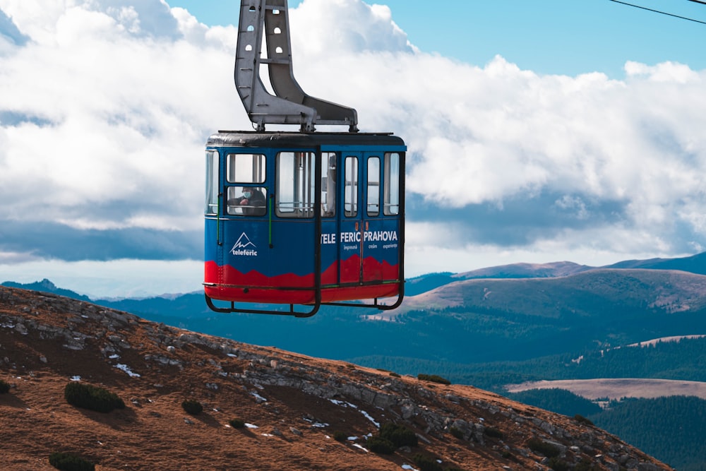 a blue and red cable car going up a hill
