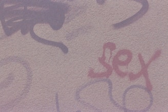 A textured wall featuring graffiti with various abstract designs and the word 'sex' written in red.