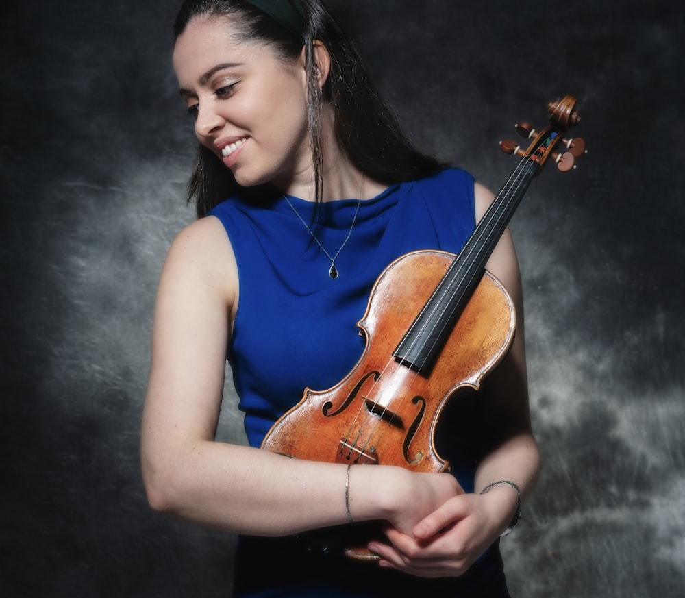 a woman in a blue dress holding a violin