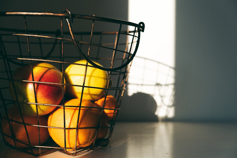 a wire basket filled with oranges on top of a table