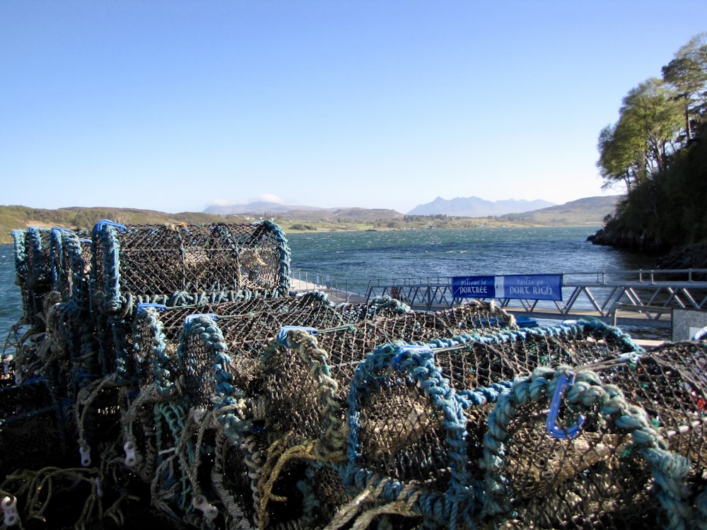 a pile of fishing nets sitting next to a body of water