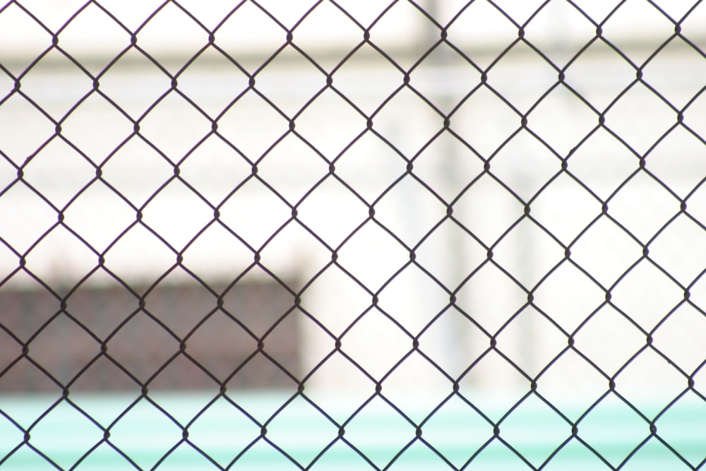 a close up of a chain link fence with a building in the background