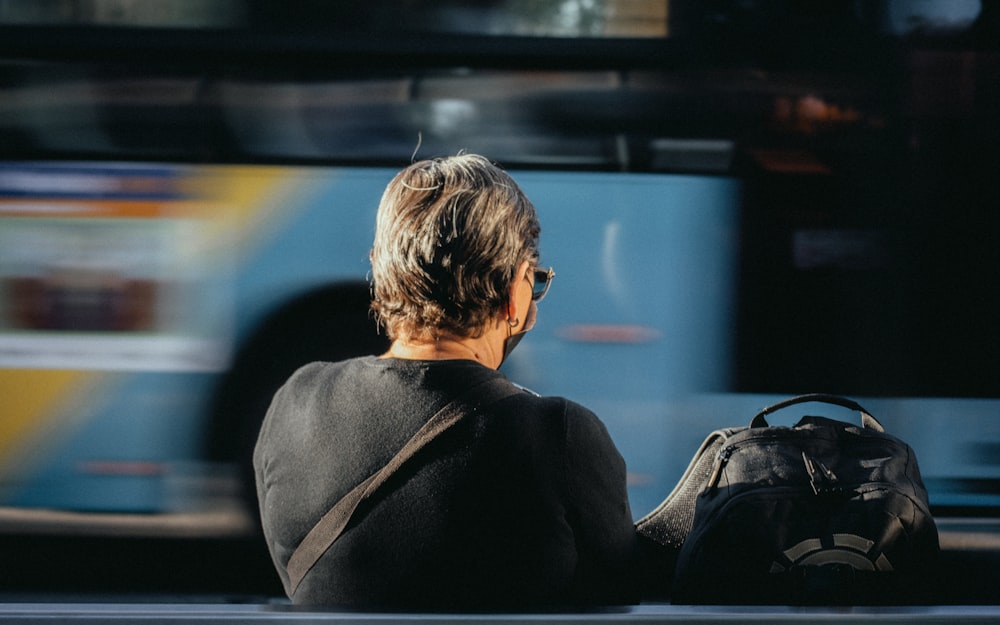 a woman sitting on a bench in front of a bus