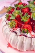 A beautifully arranged display of handcrafted pavlovas in vibrant red and pink colors.