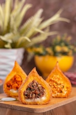 three pastries sitting on a cutting board next to a potted plant