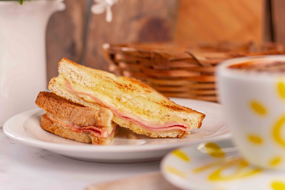 a sandwich on a plate next to a cup of coffee