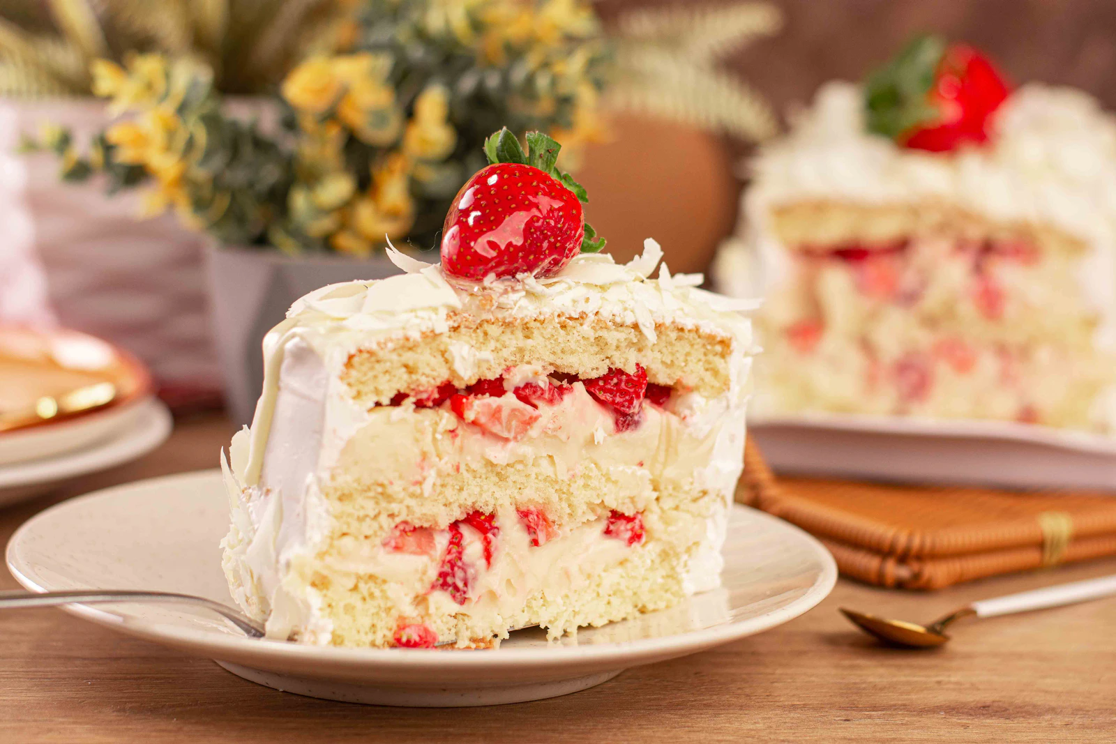 A slice of milk-soaked layer cake topped with fresh strawberries