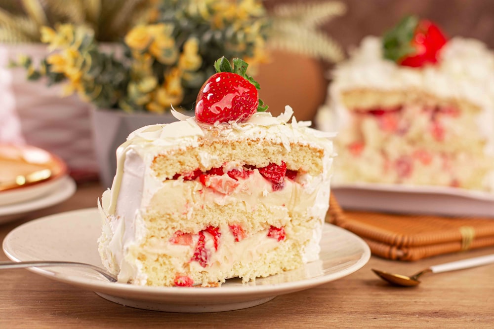 a piece of cake with white frosting and strawberries on top