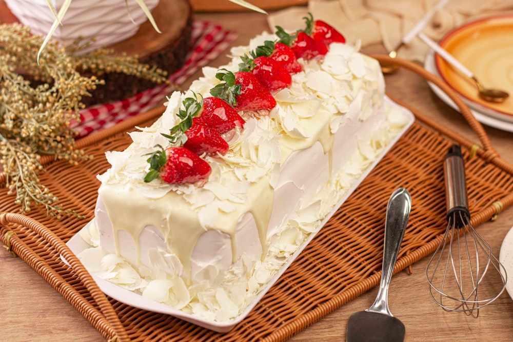 um bolo com cobertura branca e morangos por cima