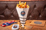 Artisan fries loaded with cheese and toppings, served in a stylish branded paper cone.