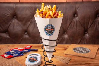 Artisan fries loaded with cheese and toppings, served in a stylish branded paper cone.