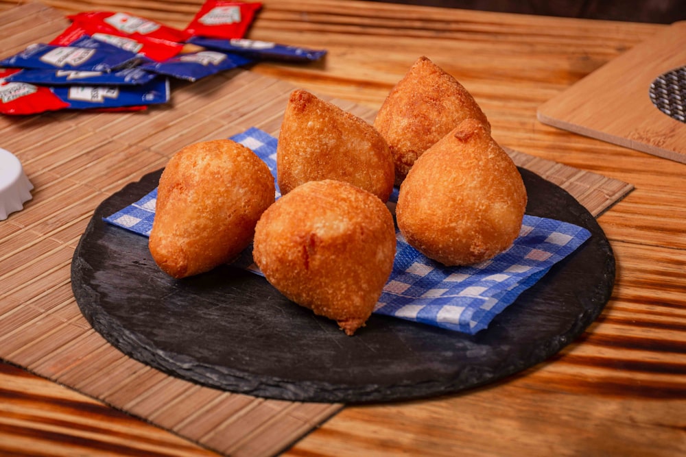 a black plate topped with fried food on top of a wooden table