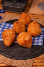 a black plate topped with fried food on top of a wooden table