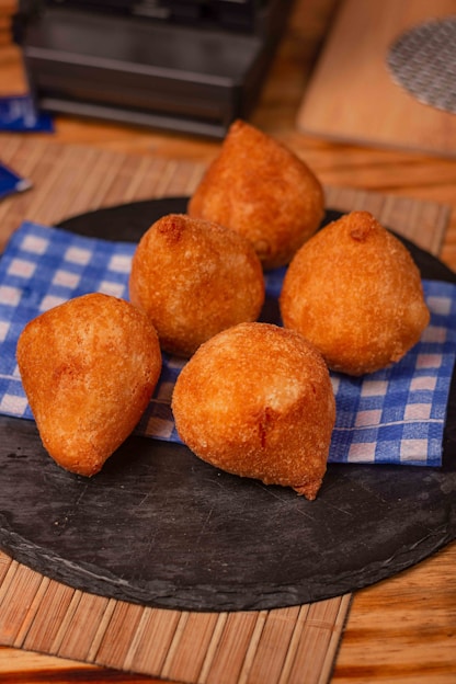 a black plate topped with fried food on top of a wooden table