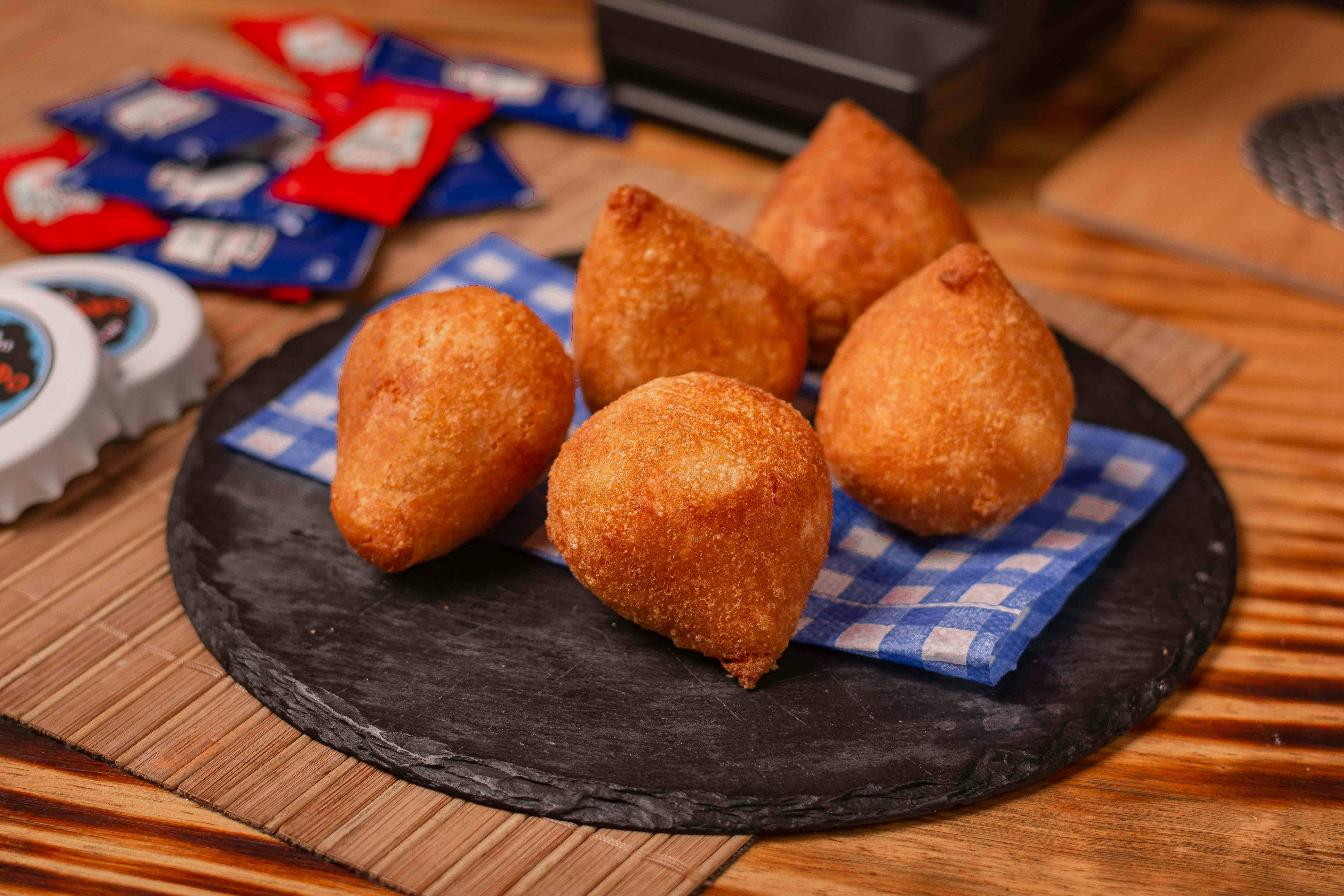 a black plate topped with fried food on top of a wooden table