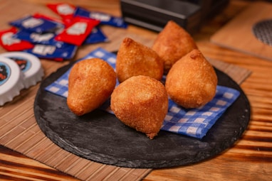 a black plate topped with fried food on top of a wooden table