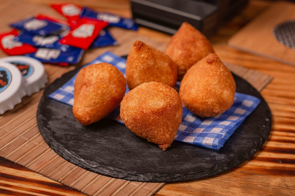 a black plate topped with fried food on top of a wooden table