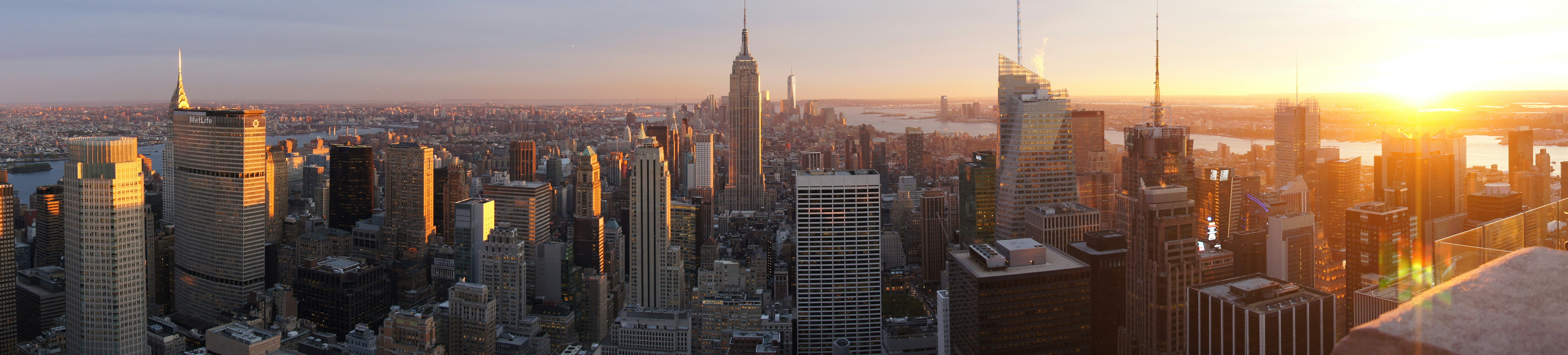 New York Manhattan skyline at sunset, golden hour light on skyscrapers, Hudson River, iconic city view