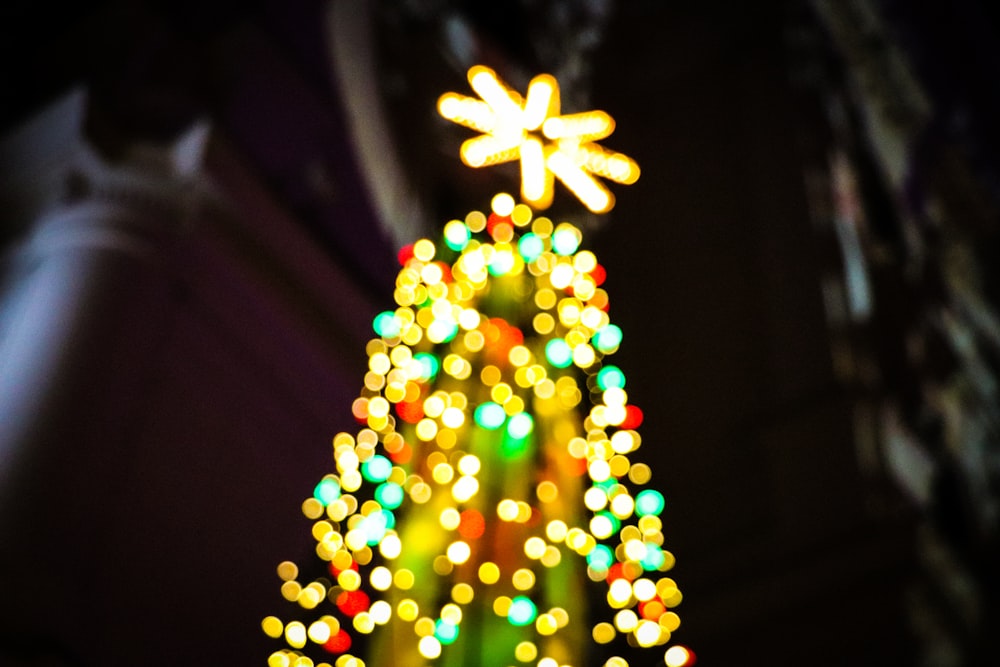 a brightly lit christmas tree in front of a building