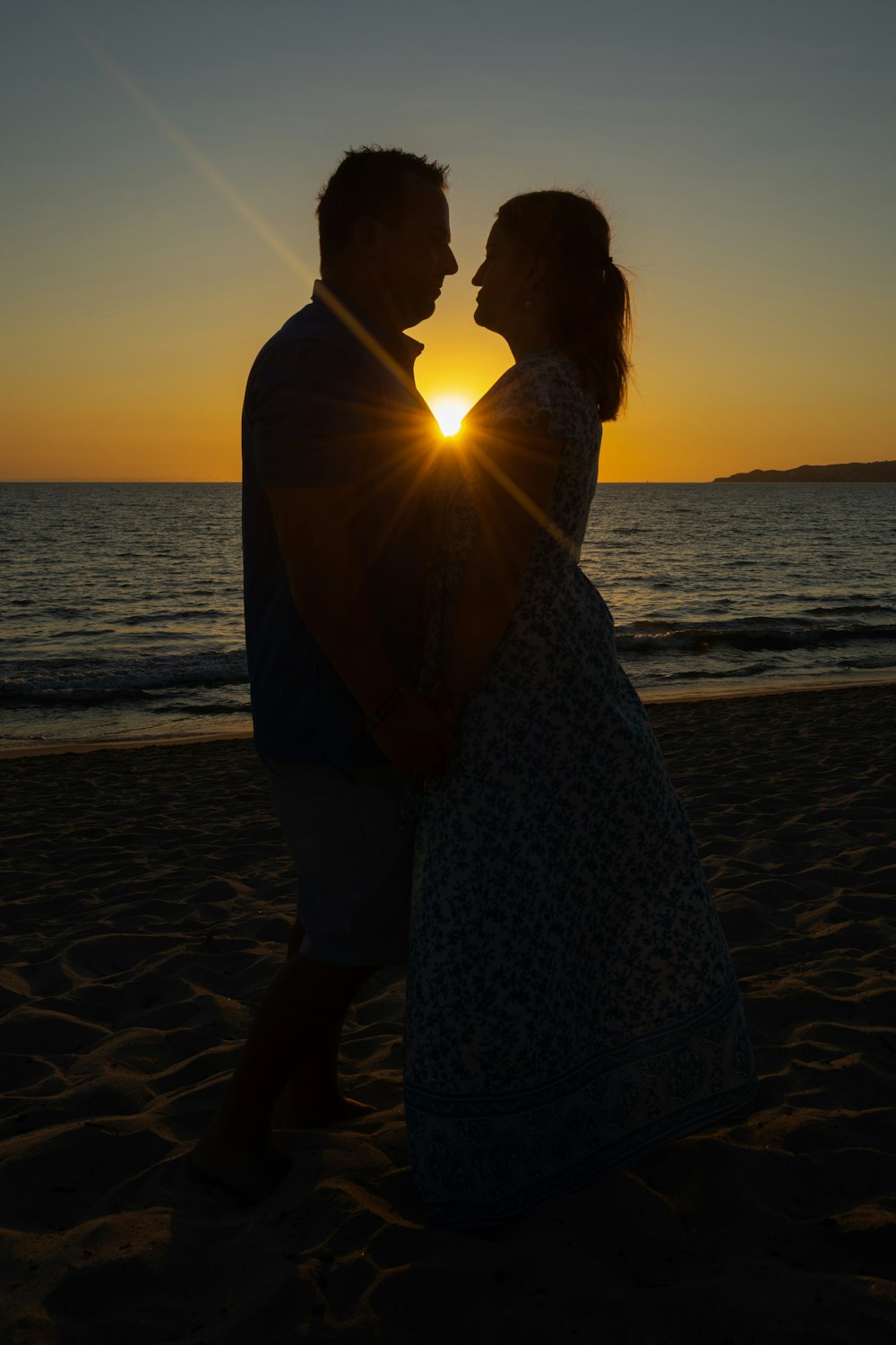 a man and woman standing on top of a sandy beach