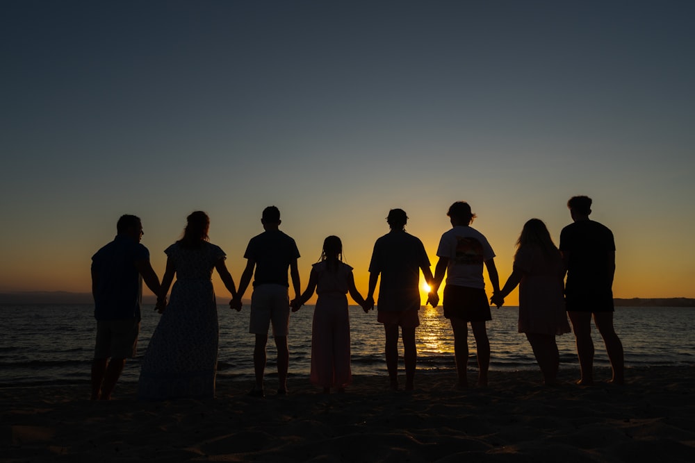 um grupo de pessoas em pé no topo de uma praia de areia