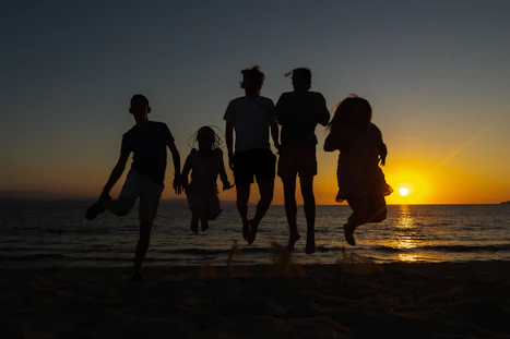 a group of people jumping on a sandy beach