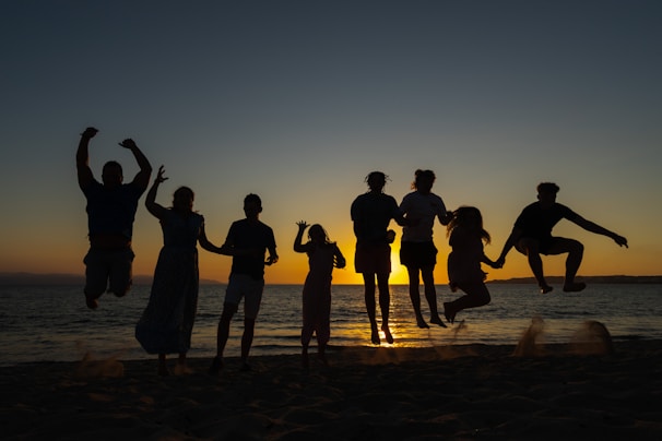 a group of people standing on top of a sandy beach