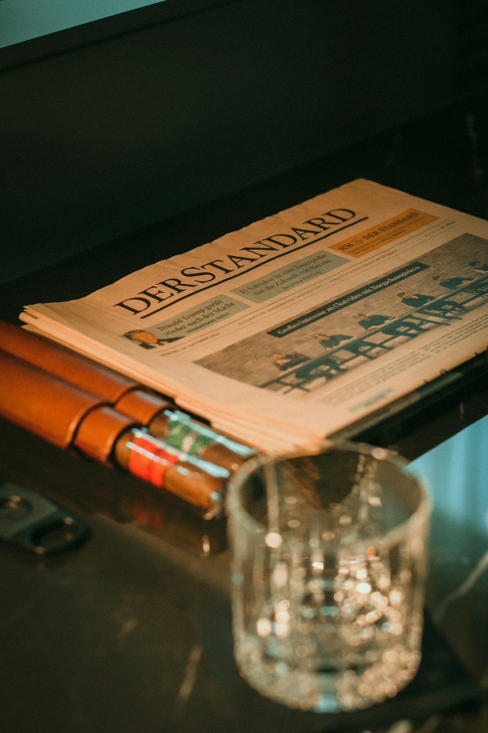 Eine Zeitung sitzt auf einem Tisch neben einem Glas