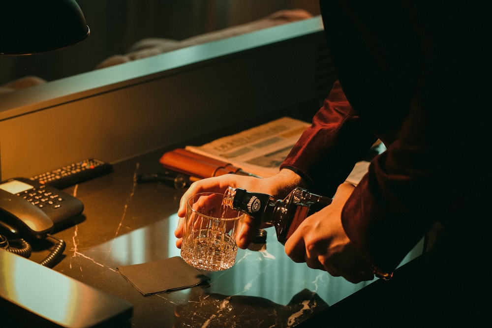 a person holding a glass of water near a phone