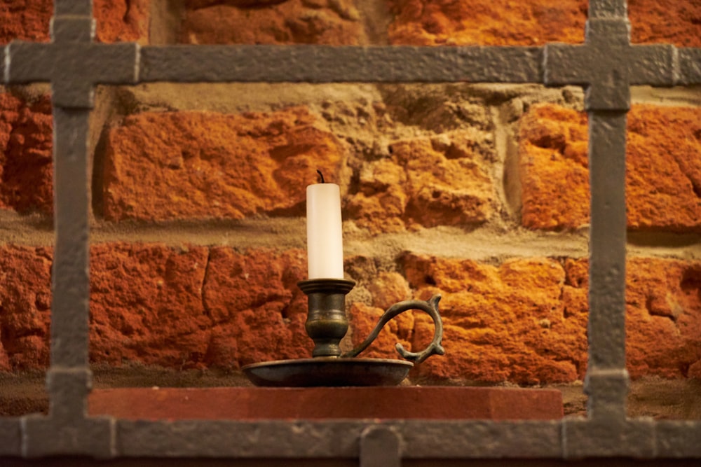 a candle is lit on a shelf in front of a brick wall