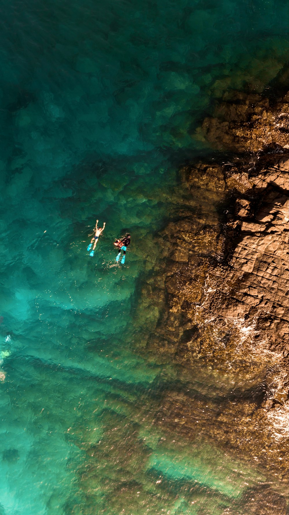 two people are swimming in the clear blue water
