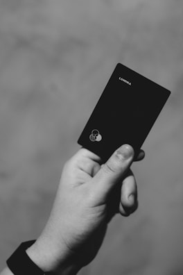 a hand holding a black cell phone in a black and white photo