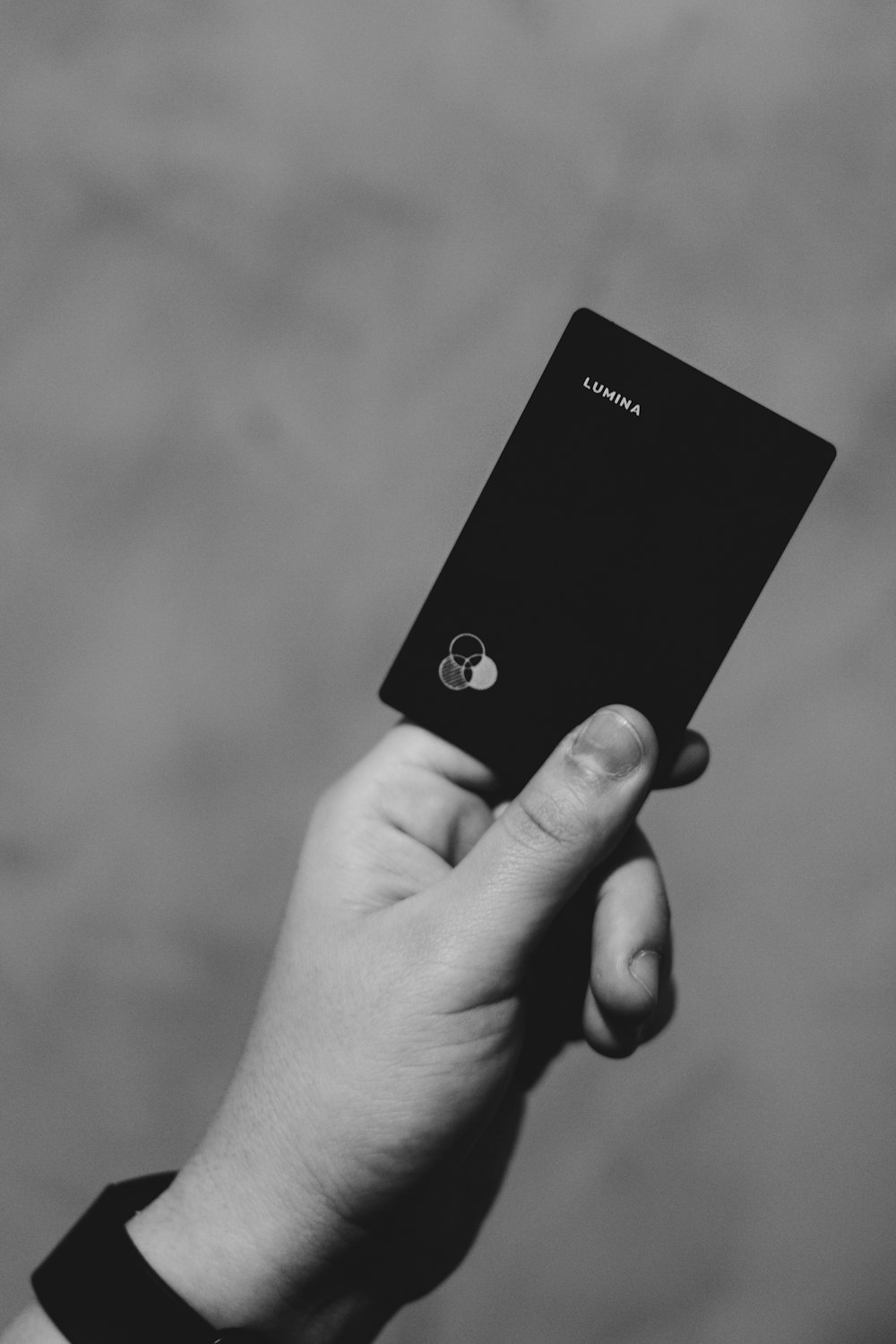 a hand holding a black cell phone in a black and white photo