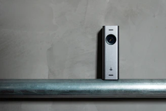 a silver camera sitting on top of a metal pole