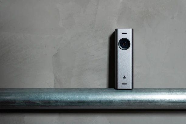 a silver camera sitting on top of a metal pole