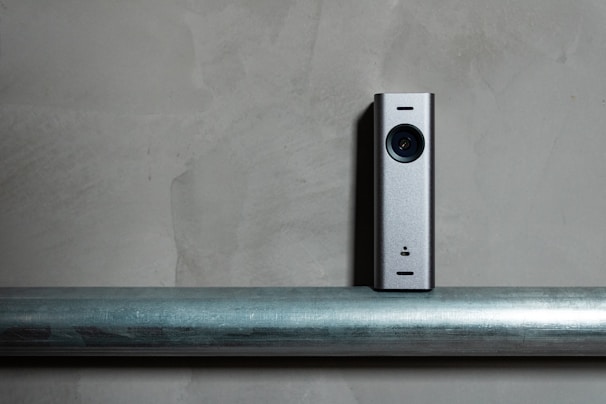 a silver camera sitting on top of a metal pole