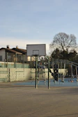 Young players practicing dribbling drills on an outdoor basketball court under clear skies.