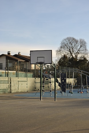 Children practicing basketball drills together on an outdoor court under a clear sky