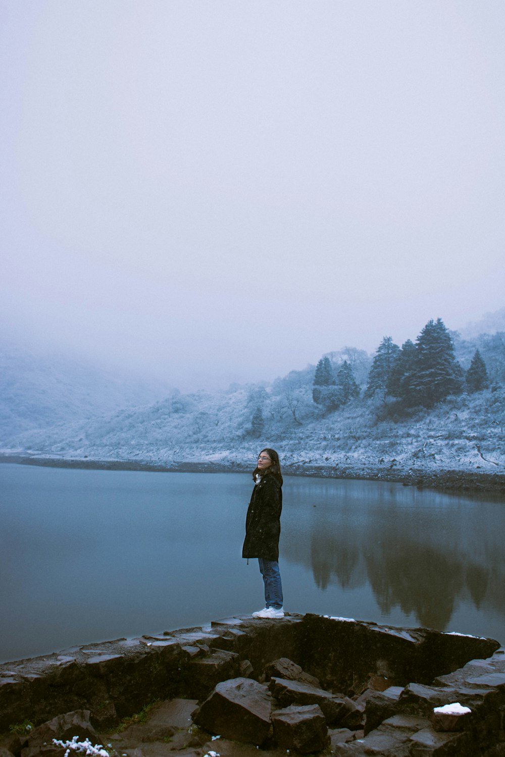 a woman standing on the edge of a body of water