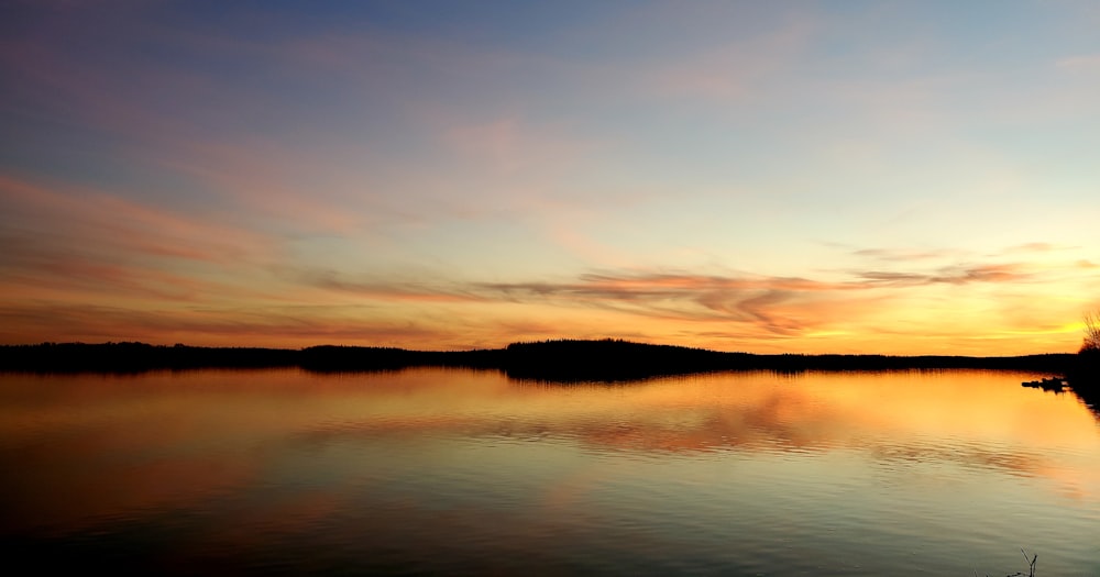 a sunset over a lake with a boat in the water