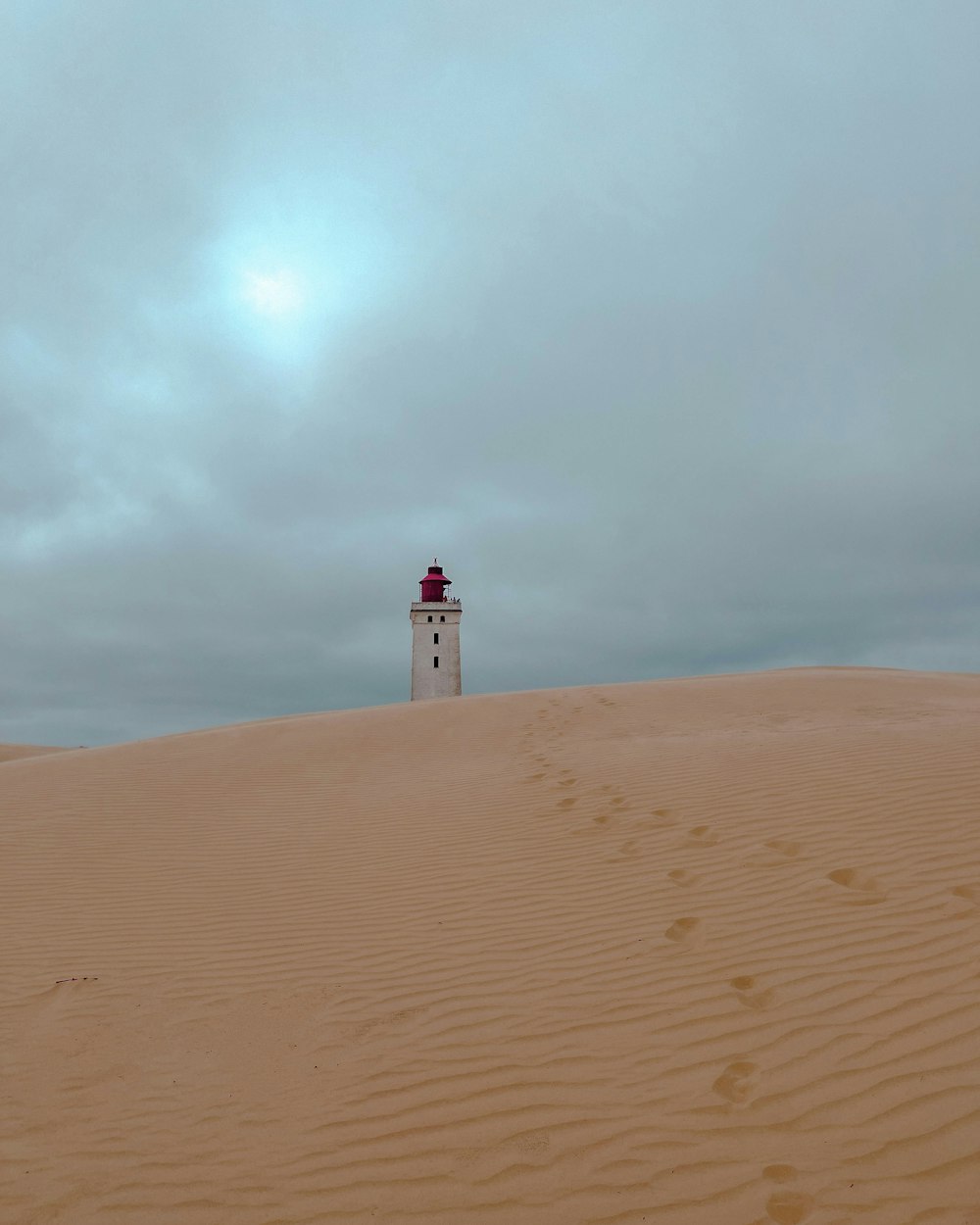 a lighthouse on top of a sand dune